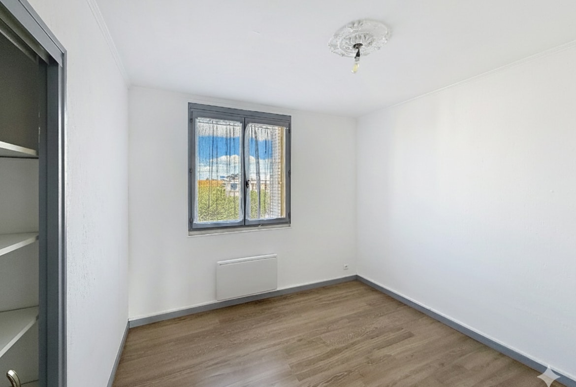 Cette image montre l'une des chambres de l'appartement à Avignon. La pièce est claire, avec une fenêtre et un parquet au sol.