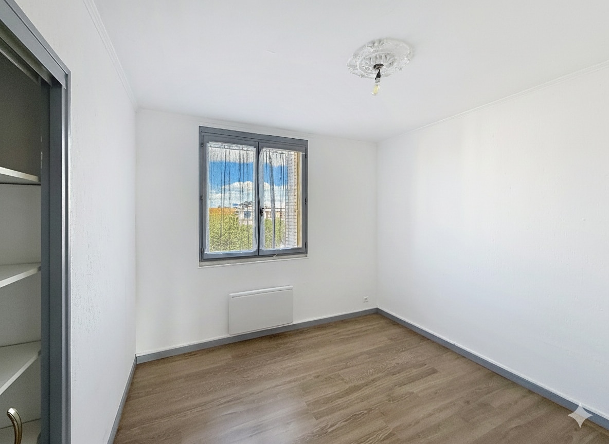 Cette image montre l'une des chambres de l'appartement à Avignon. La pièce est claire, avec une fenêtre et un parquet au sol.