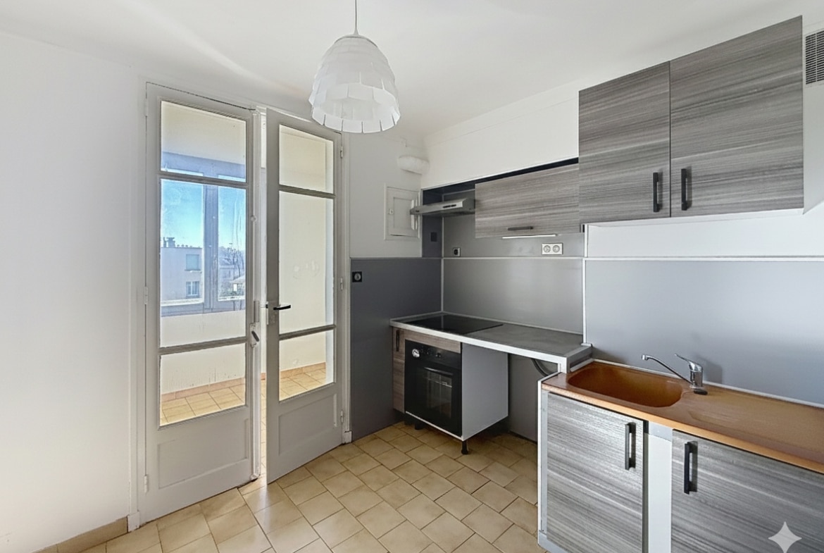 La photo dévoile la cuisine de l'appartement à Avignon, configurée en semi-ouverte. Elle est équipée de rangements et donne accès à une loggia