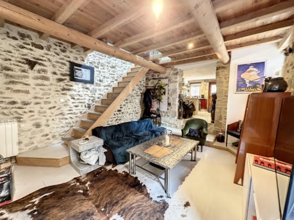 Salon avec mur en pierre et poutres apparentes neuves