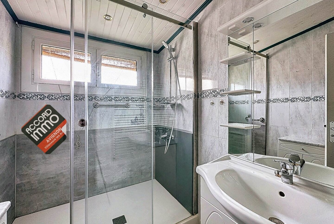 Salle d'eau équipée d'une douche moderne, d'une vasque et de carrelage élégant, située dans une maison avec jardin en vente au Pontet.