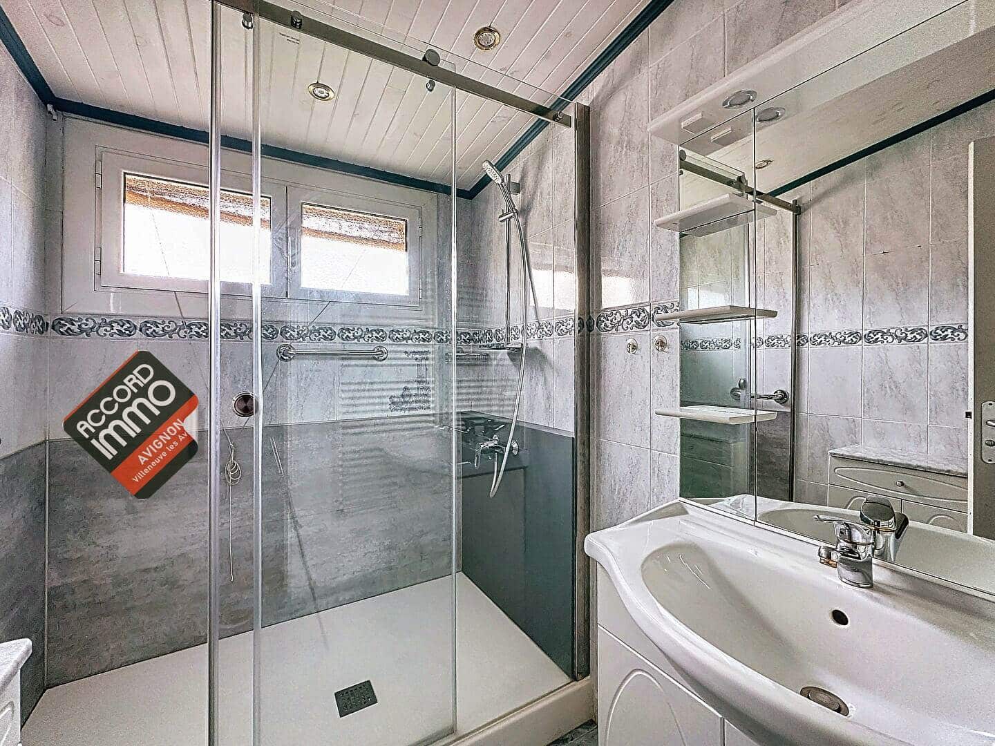 Salle d'eau équipée d'une douche moderne, d'une vasque et de carrelage élégant, située dans une maison avec jardin en vente au Pontet.