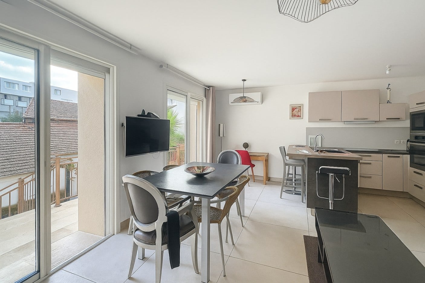 Grande pièce à vivre avec cuisine équipée et coin repas donnant sur la terrasse d’un T4 meublé à Avignon