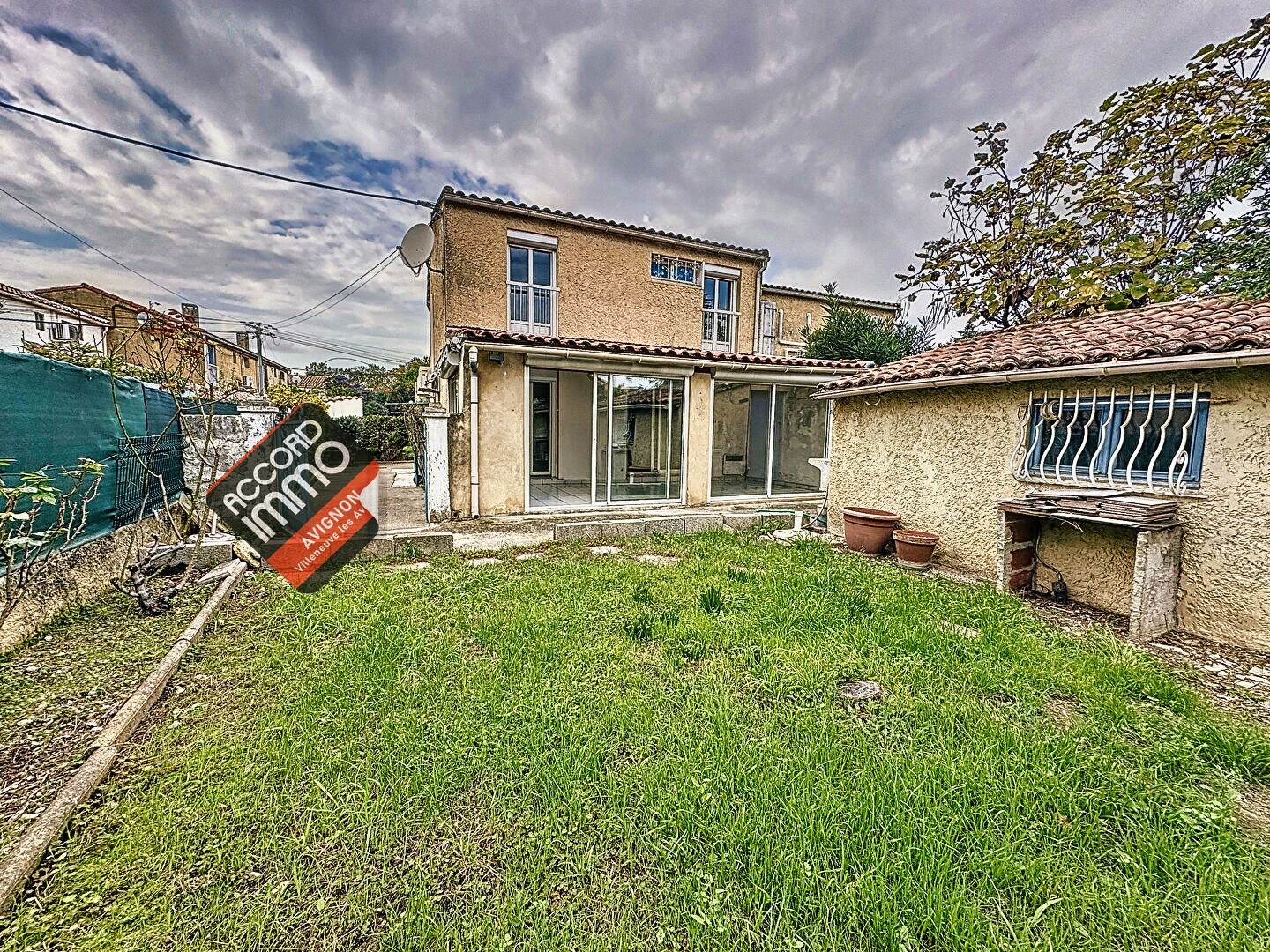 Vue extérieure d'une maison avec jardin, terrasse et dépendances, située au Pontet, maison en vente.