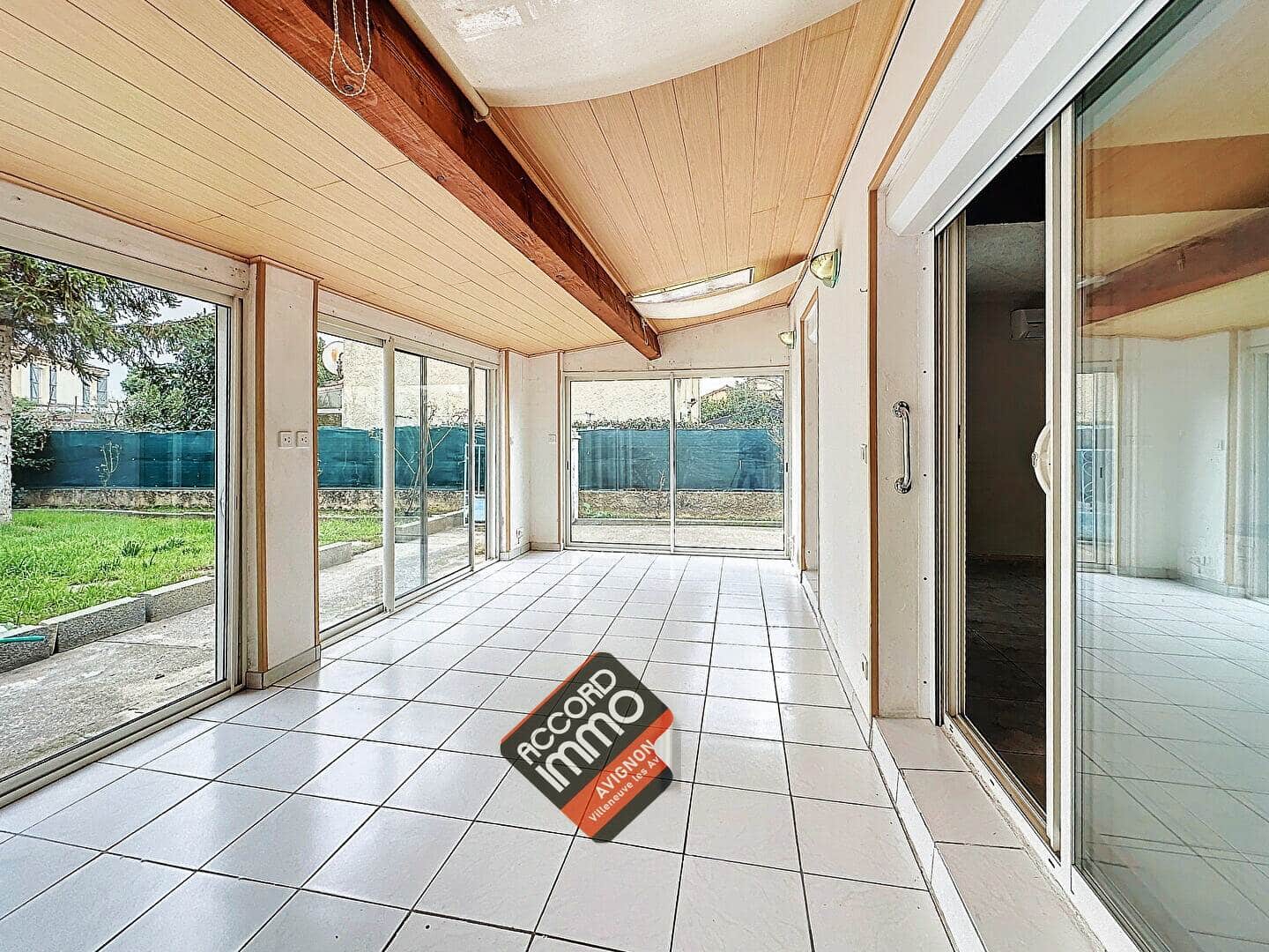 Véranda avec grandes baies vitrées donnant sur le jardin, dans une maison à vendre au Pontet.