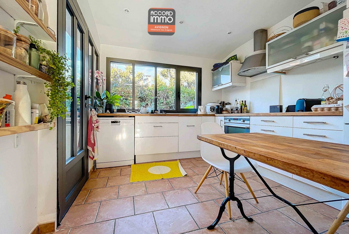 Cuisine fonctionnelle avec rangements, plan de travail en bois et fenêtre donnant sur le jardin, située dans une maison à vendre à Avignon