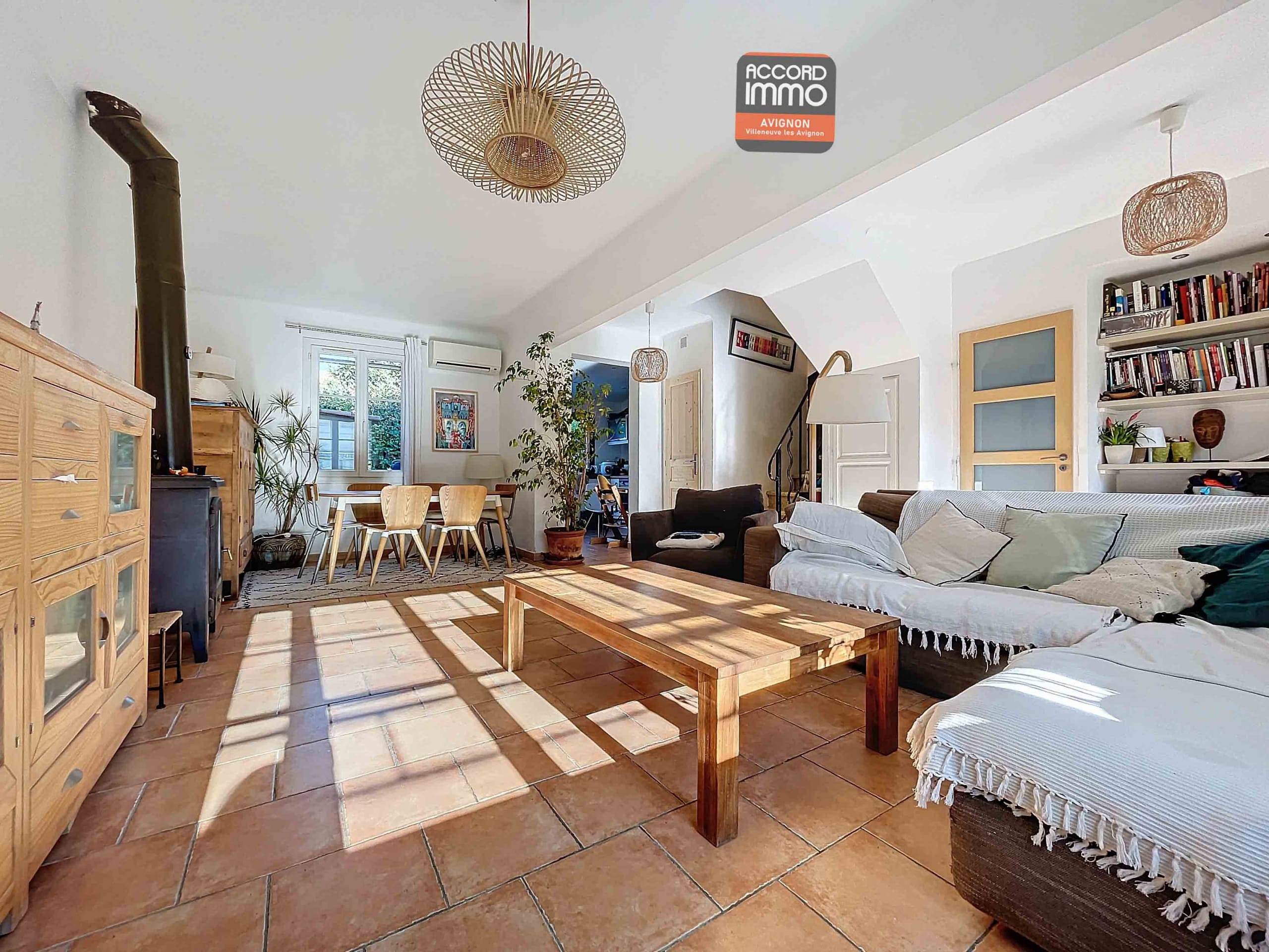 Salon avec carrelage au sol et espace salle à manger, doté de baies vitrées offrant une vue sur le jardin