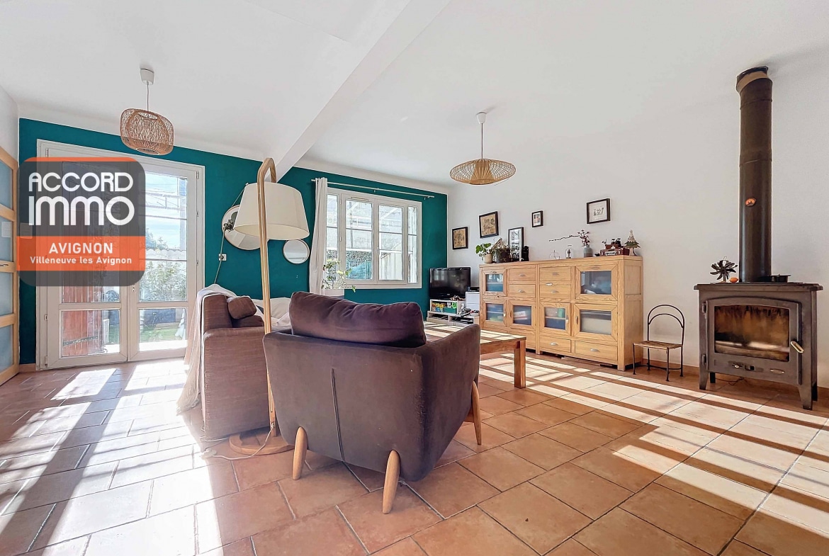 Salon avec poêle, mobilier et lumière naturelle, offrant un accès direct aux pièces principales d'une maison avec jardin à Avignon