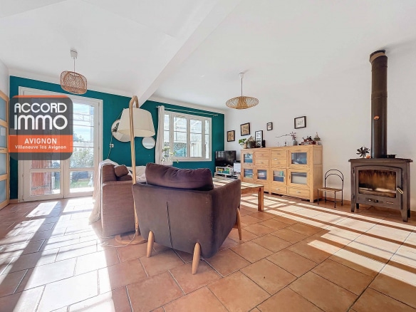 Salon avec poêle, mobilier et lumière naturelle, offrant un accès direct aux pièces principales d'une maison avec jardin à Avignon
