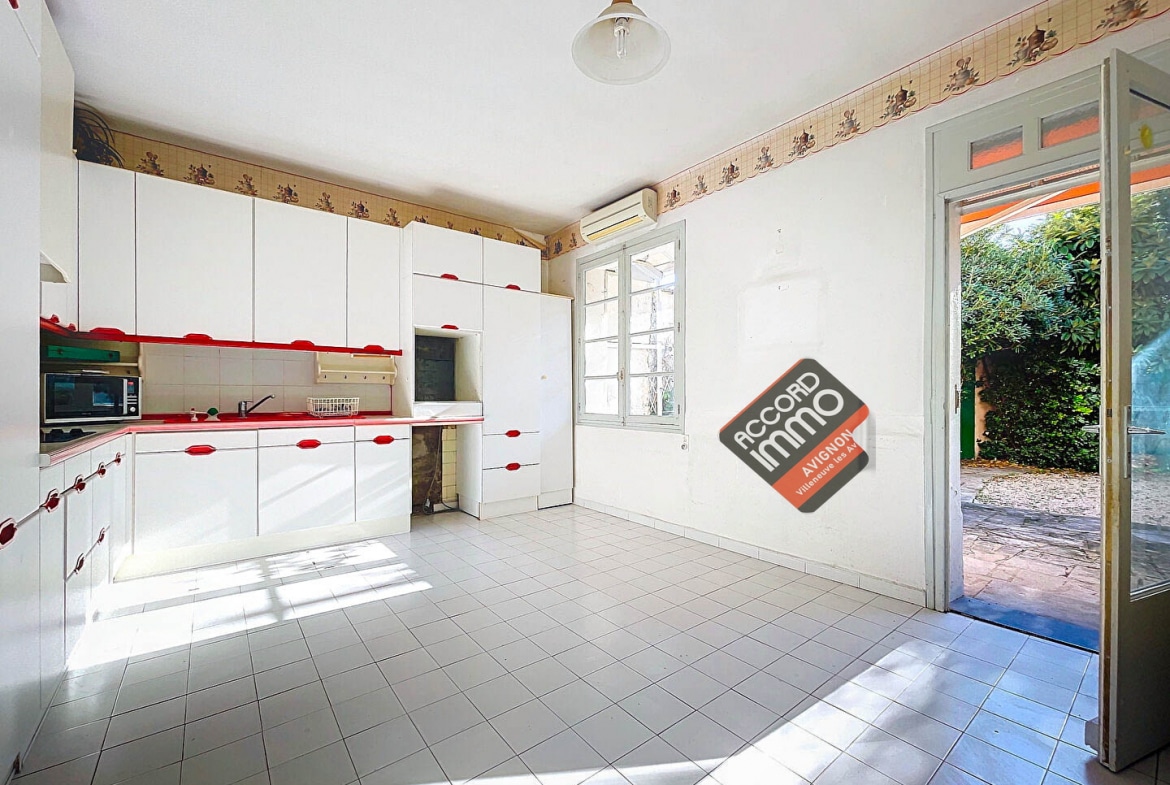 Vue d'une cuisine équipée dans une maison située à Avignon. L'espace est aménagé avec des rangements intégrés, un sol en carrelage et bénéficie d'un accès direct à l'extérieur