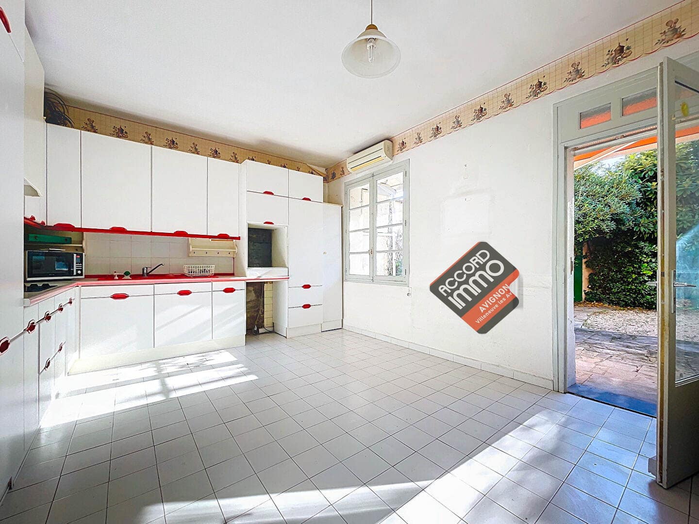 Vue d'une cuisine équipée dans une maison située à Avignon. L'espace est aménagé avec des rangements intégrés, un sol en carrelage et bénéficie d'un accès direct à l'extérieur