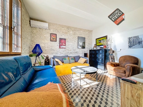 Salon spacieux d'une maison en pierre à Avignon, avec lumière naturelle, décoration moderne et sol en carreaux de ciment