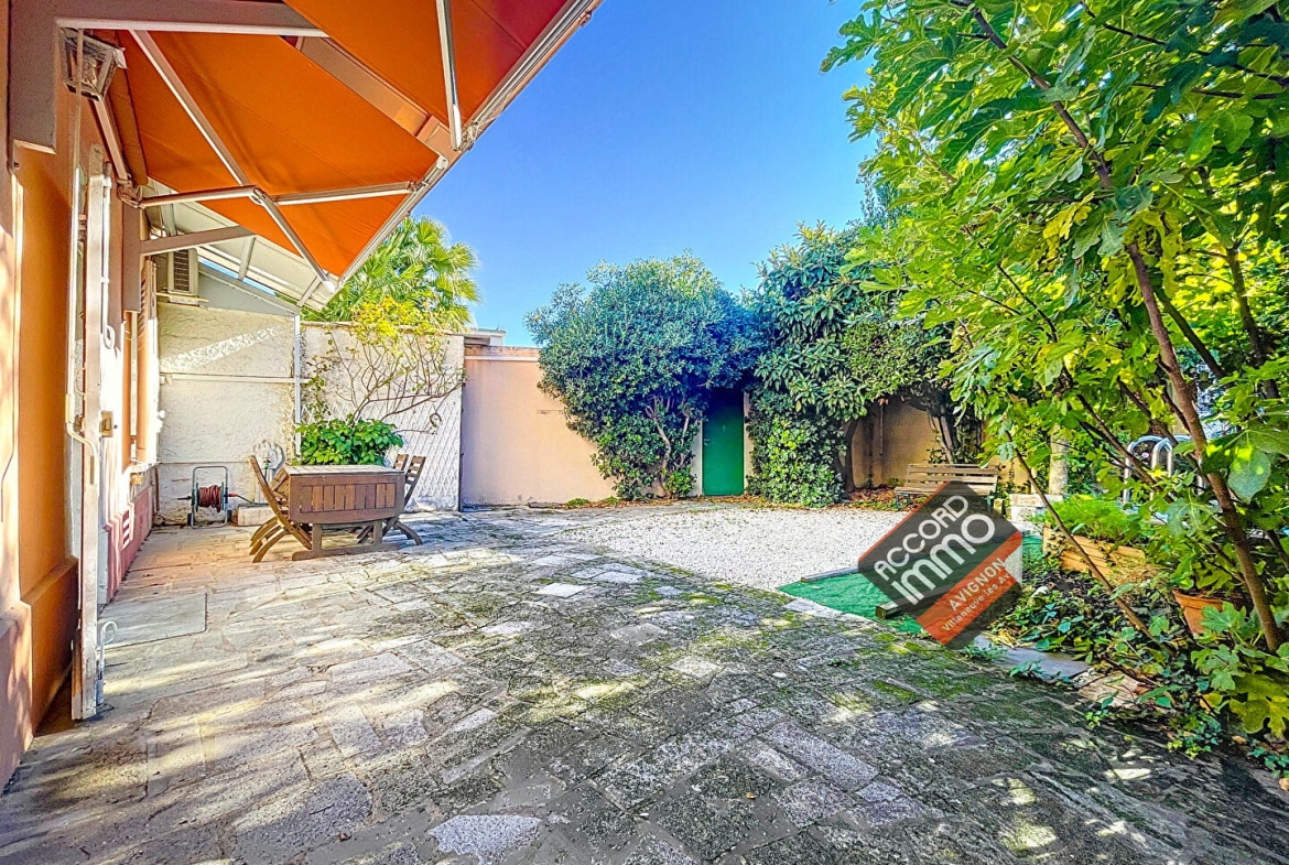 Charmant jardin ombragé avec une grande terrasse en pierre, entouré de verdure dans une maison familiale située dans le quartier Trillade à Avignon