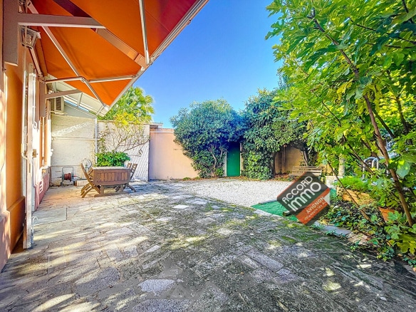 Charmant jardin ombragé avec une grande terrasse en pierre, entouré de verdure dans une maison familiale située dans le quartier Trillade à Avignon