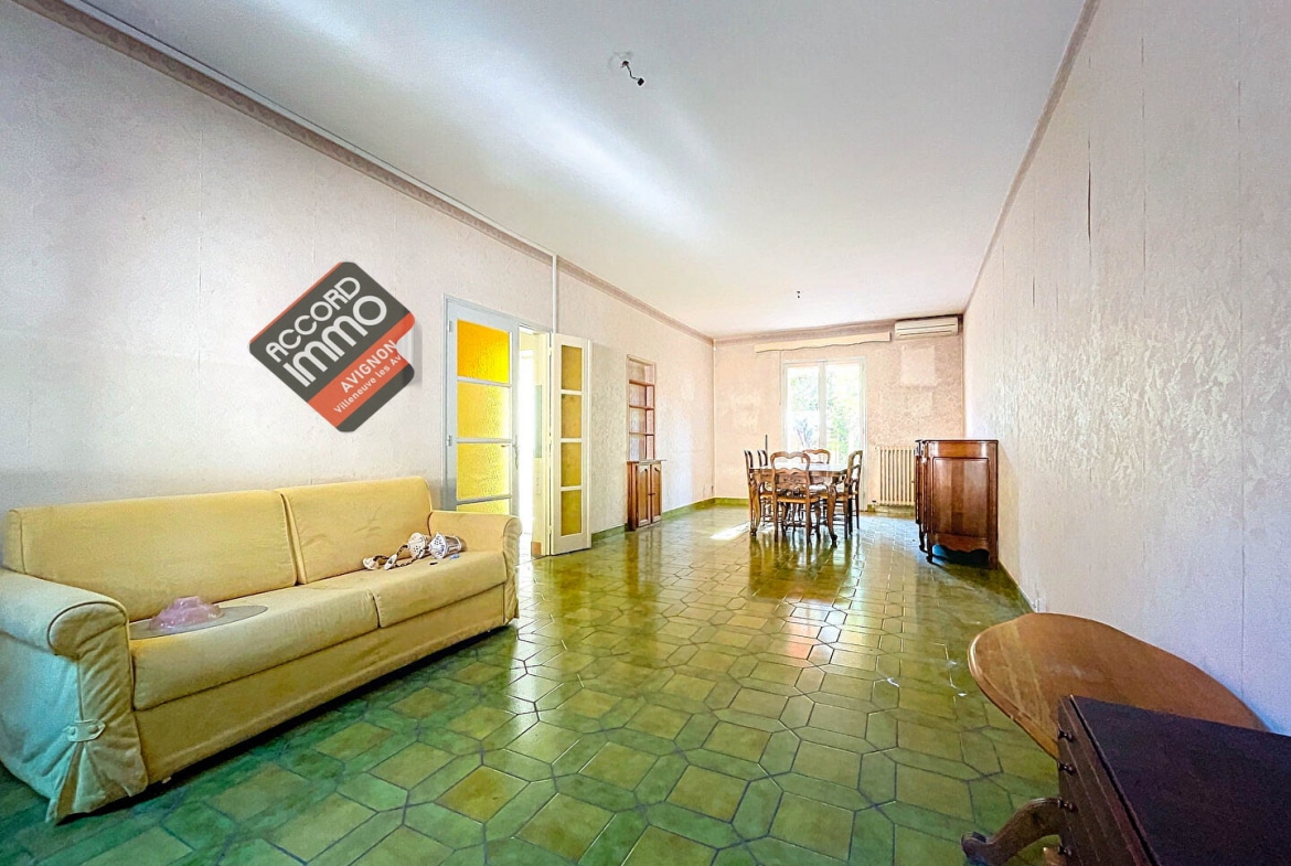 Séjour spacieux et lumineux avec sol en carrelage vert, mobilier classique et une grande table à manger, situé dans une maison T5 à vendre à Avignon