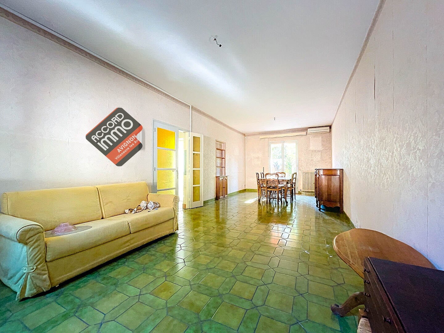 Séjour spacieux et lumineux avec sol en carrelage vert, mobilier classique et une grande table à manger, situé dans une maison T5 à vendre à Avignon