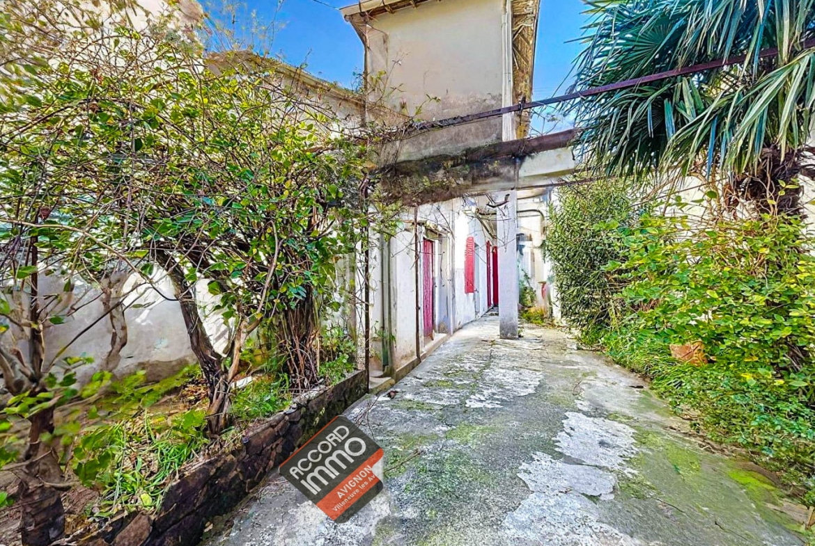 Cour pavée entourée de végétation donnant accès à un immeuble de rapport situé à Avignon. Bien immobilier proposé à la vente pour un investissement locatif