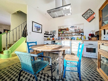Cette photo met en avant une cuisine semi-ouverte équipée, offrant un mélange harmonieux de décor rustique et moderne. Située dans une maison à vendre dans le quartier des Rotondes à Avignon