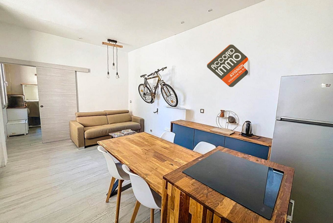 Salon avec canapé, table à manger en bois et rangements dans une maison T2 près des remparts d'Avignon.