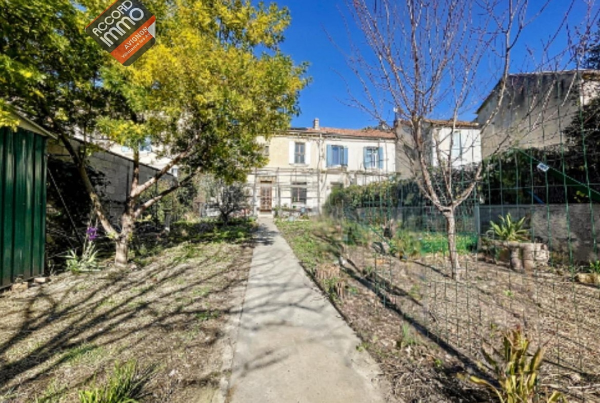 Vue extérieure d'une maison en pierre à vendre à Avignon, quartier extramuros, avec un jardin arboré et un chemin d’accès