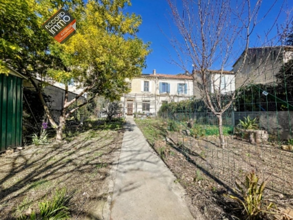 Vue extérieure d'une maison en pierre à vendre à Avignon, quartier extramuros, avec un jardin arboré et un chemin d’accès