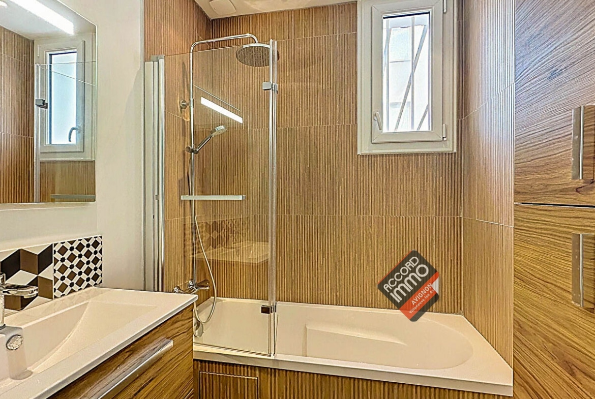 Salle de bain élégante avec baignoire, douche vitrée et meuble en bois dans une maison à Avignon