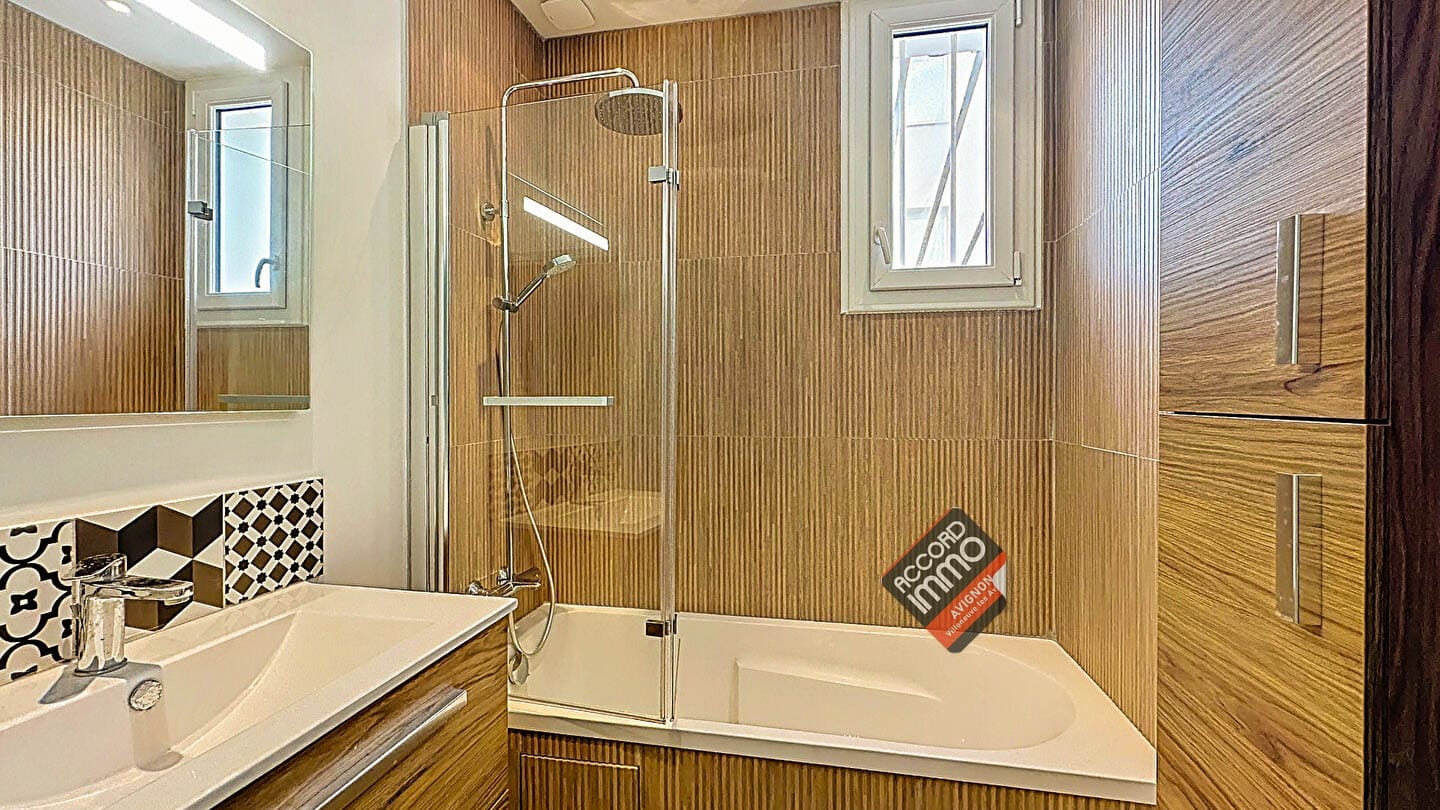 Salle de bain élégante avec baignoire, douche vitrée et meuble en bois dans une maison à Avignon
