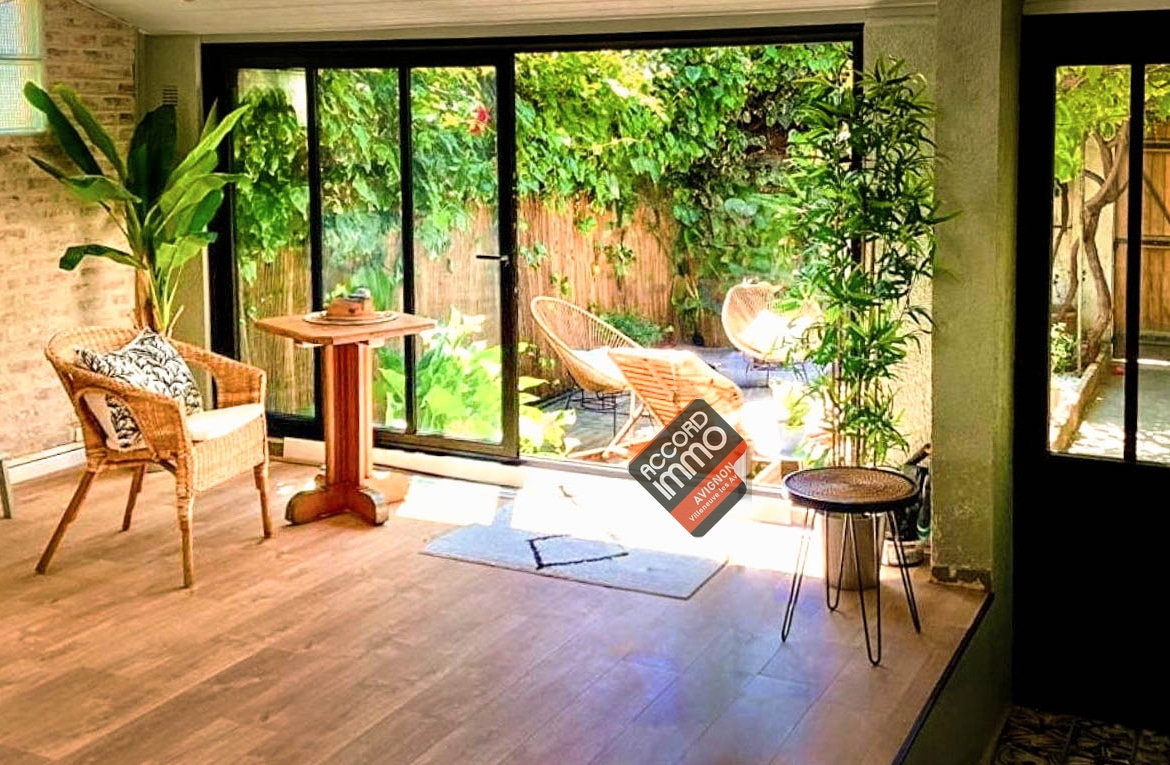 Salon cosy dans une véranda lumineuse avec baie vitrée ouvrant sur un jardin à Avignon