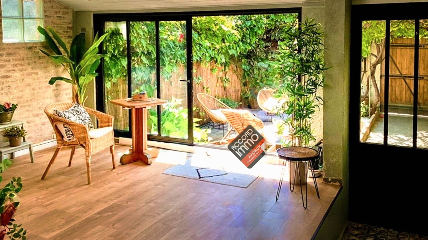 Salon cosy dans une véranda lumineuse avec baie vitrée ouvrant sur un jardin à Avignon