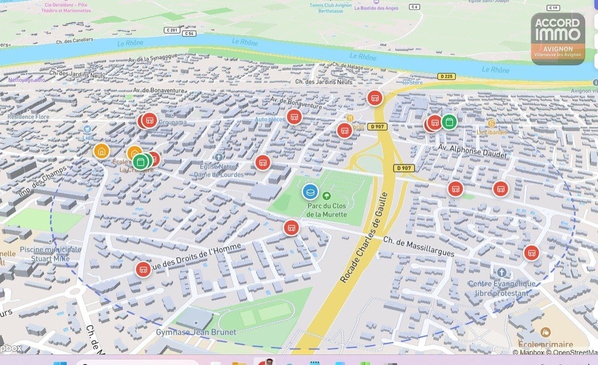 Vue cartographique en 3D du quartier de Villeneuve-lès-Avignon montrant les rues, le Rhône et les commerces environnants. Points d'intérêt indiqués incluant écoles, parcs et axes routiers principaux.