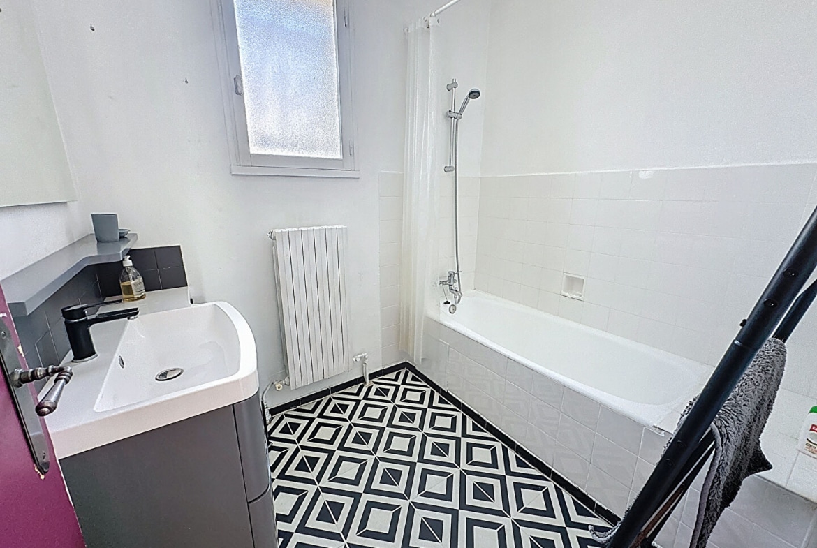 Salle de bain lumineuse avec baignoire, lavabo contemporain et carrelage graphique