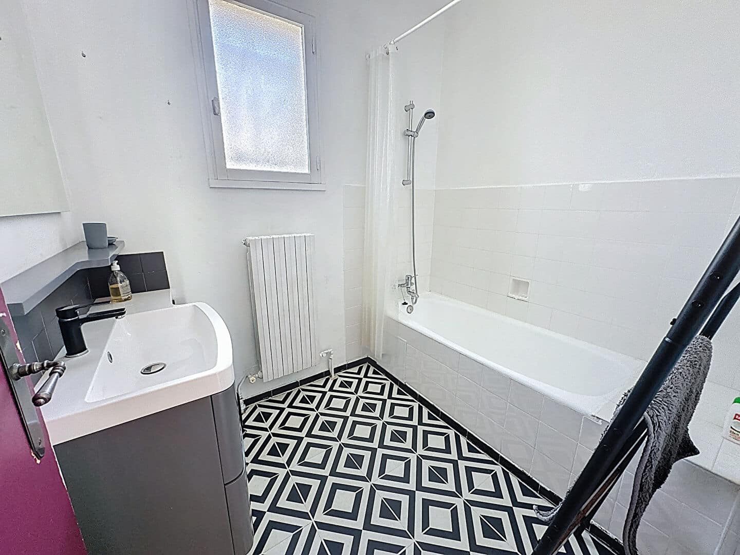 Salle de bain lumineuse avec baignoire, lavabo contemporain et carrelage graphique