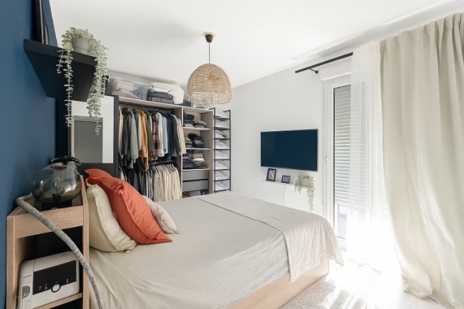 Chambre claire avec dressing ouvert, literie double et porte-fenêtre donnant sur la terrasse à Aramon