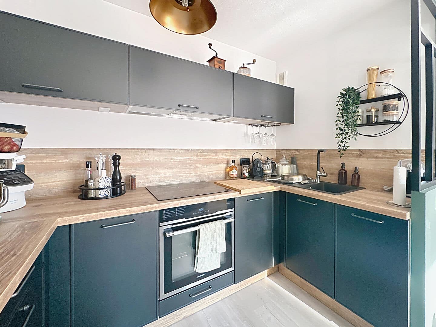 Cuisine moderne avec meubles foncés, plan de travail en bois et électroménager intégré à Aramon