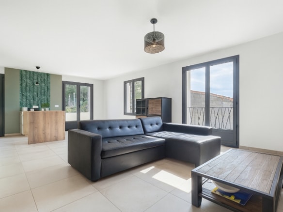 Grand salon lumineux avec canapé d’angle et baies vitrées dans une maison contemporaine à Vacqueyras