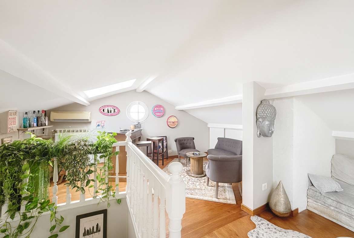 Espace détente sous combles avec fauteuils et poutres apparentes dans une maison à vendre à Avignon