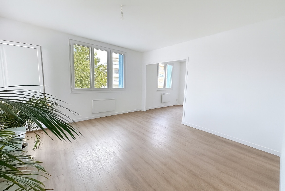 Salon lumineux avec trois fenêtres et parquet clair dans un appartement T4 à vendre à Avignon extramuros