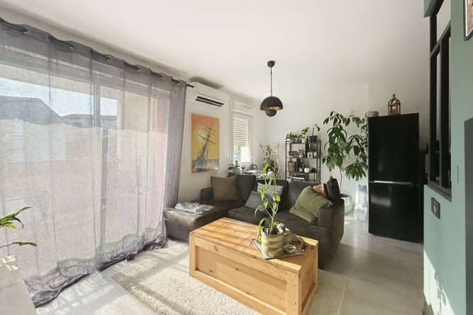 Salon moderne avec canapé, baie vitrée et ouverture sur la terrasse dans un appartement à Aramon