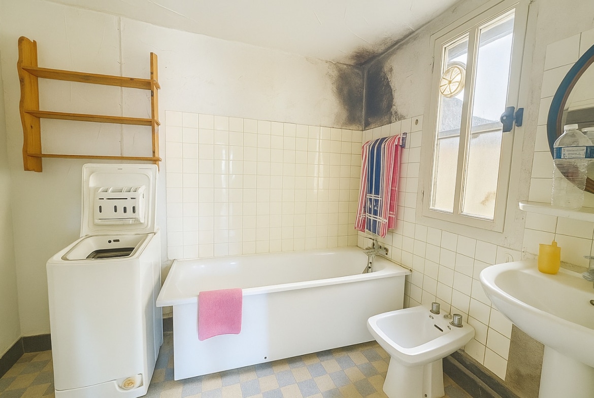 Salle de bain lumineuse avec baignoire, bidet et traces d’humidité à rénover à Avignon