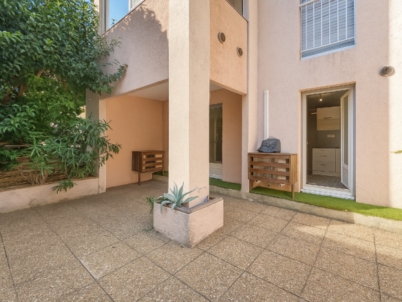 Grande terrasse dallée et arborée d’un appartement T2 en vente à Avignon, secteur Gambetta, avec accès direct depuis le séjour.