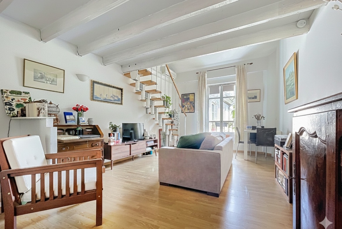 Chambre aménagée sous les toits avec poutres en bois apparentes, mobilier moderne et dressings intégrés. Espace nuit lumineux au dernier étage d'un appartement dans hôtel particulier à Avignon.