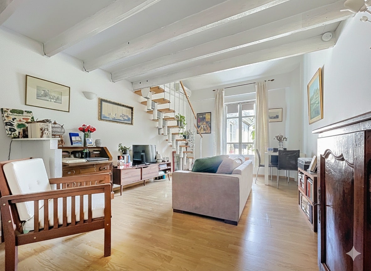 Chambre aménagée sous les toits avec poutres en bois apparentes, mobilier moderne et dressings intégrés. Espace nuit lumineux au dernier étage d'un appartement dans hôtel particulier à Avignon.