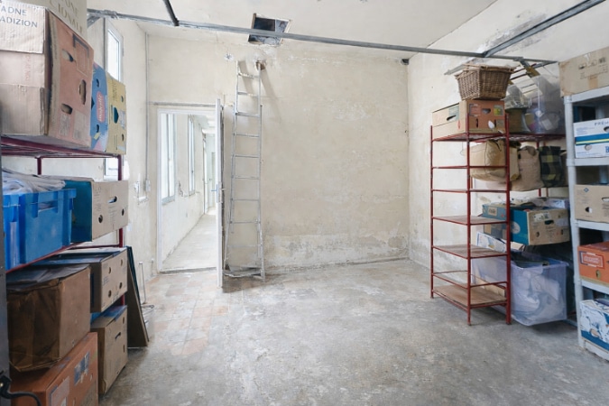 Garage de 17 m² nécessitant des travaux de rénovation avec étagères de rangement et accès direct depuis l'habitation. Espace de stationnement couvert communiquant avec la maison T2 à vendre Avignon secteur Route de Lyon