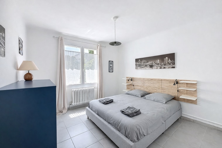 Chambre de 12 m² de plain-pied avec fenêtre PVC double vitrage et radiateur. Sol carrelé et murs neutres offrant possibilités d'aménagement personnalisé.