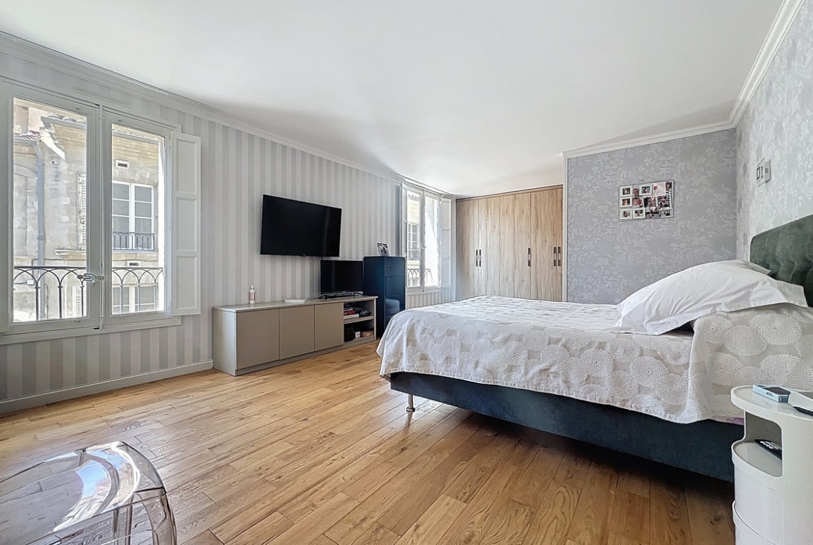 Chambre avec lit et mobilier positionné contre les murs peints dans des tons neutres. Une des quatre chambres de cet appartement situé près du Palais des Papes.