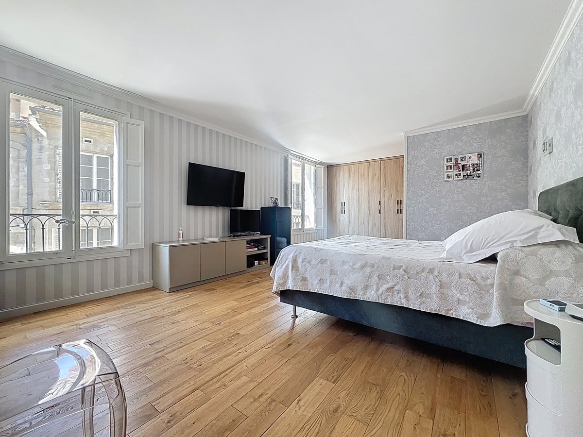 Chambre avec lit et mobilier positionné contre les murs peints dans des tons neutres. Une des quatre chambres de cet appartement situé près du Palais des Papes.