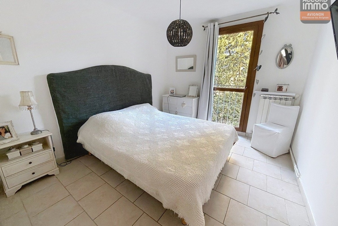 Chambre avec murs clairs et sol stratifié, fenêtre à volet roulant donnant sur l'extérieur. Porte d'entrée en bois ouvrant sur le couloir de distribution du logement.