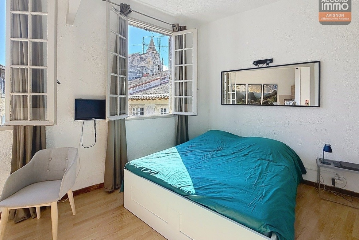 chambre avec lit simple ou double, murs clairs et sol carrelé ou parquet. Fenêtre laissant entrer la lumière naturelle, mobilier minimaliste adapté au format T1.