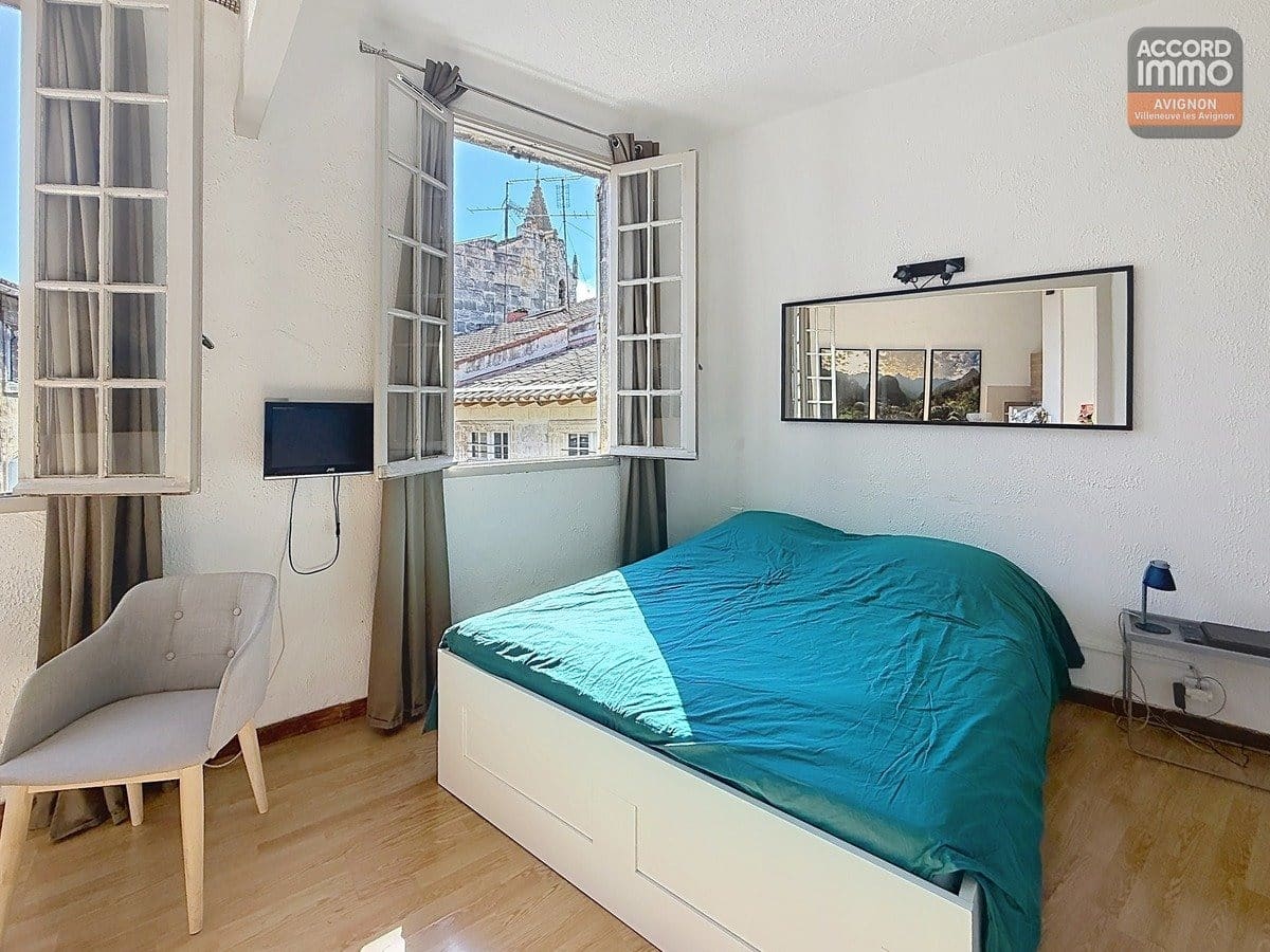 chambre avec lit simple ou double, murs clairs et sol carrelé ou parquet. Fenêtre laissant entrer la lumière naturelle, mobilier minimaliste adapté au format T1.