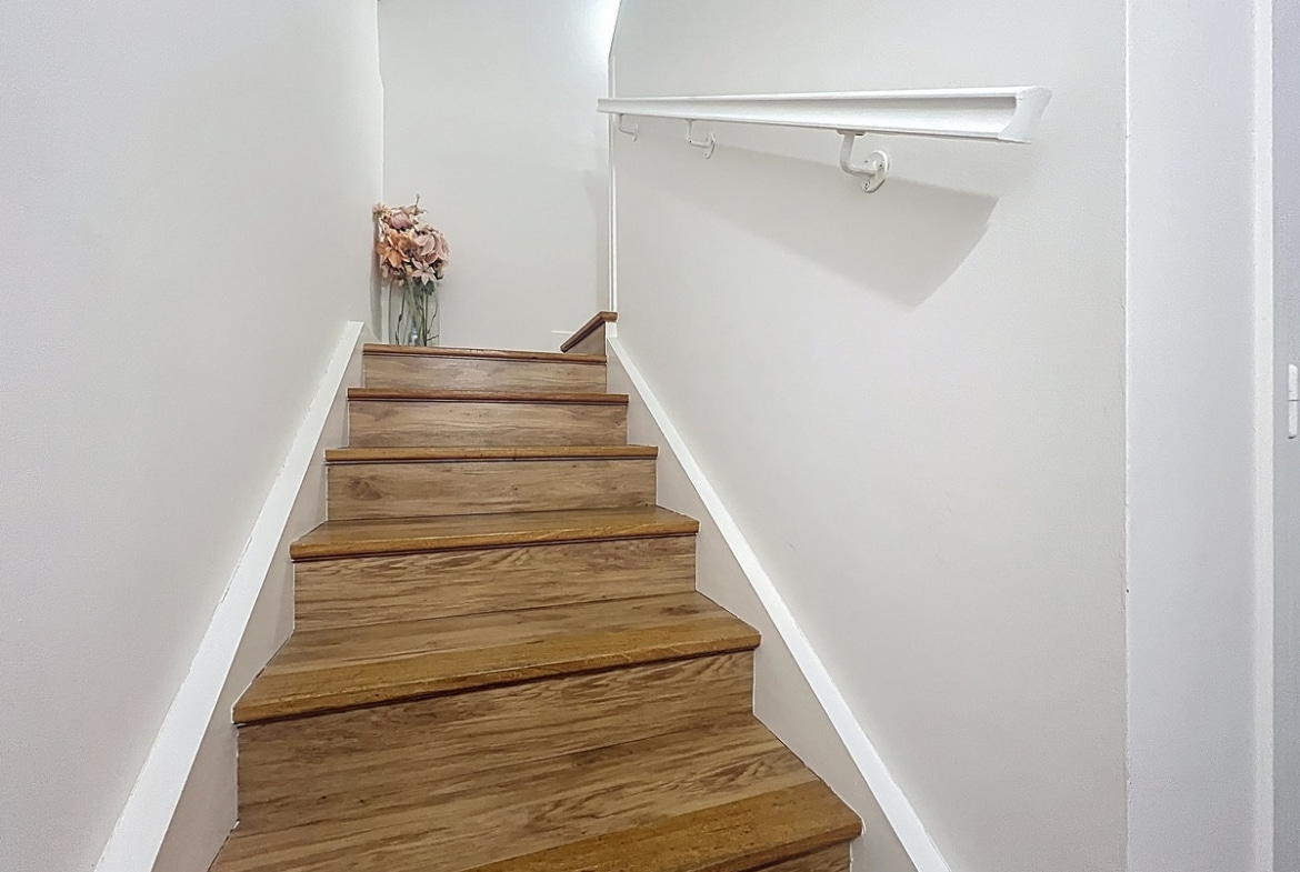 Couloir desservant les différentes pièces du duplex avec portes alignées et sol uniforme. Espace de circulation intérieur reliant les deux niveaux de l'appartement.